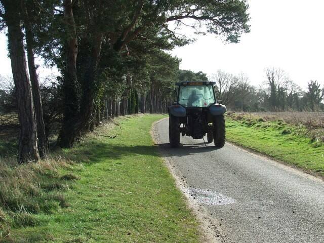 A tractor driving towards the camera along a country lane