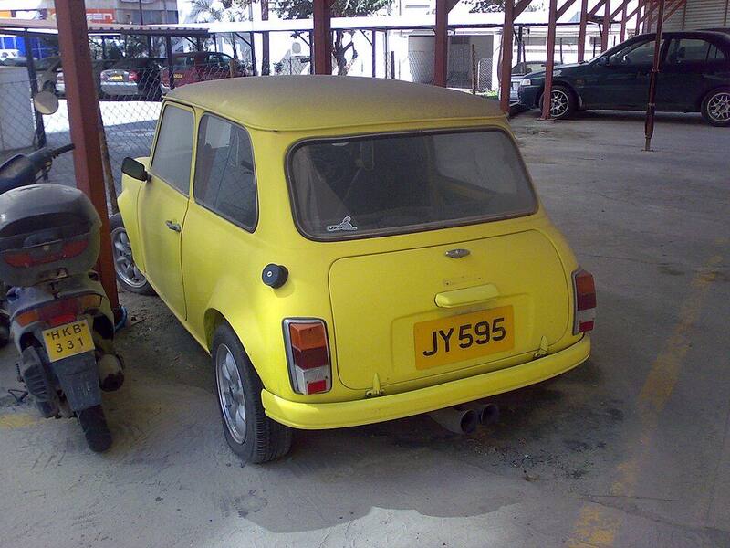 A yellow classic Mini parked under a canopy